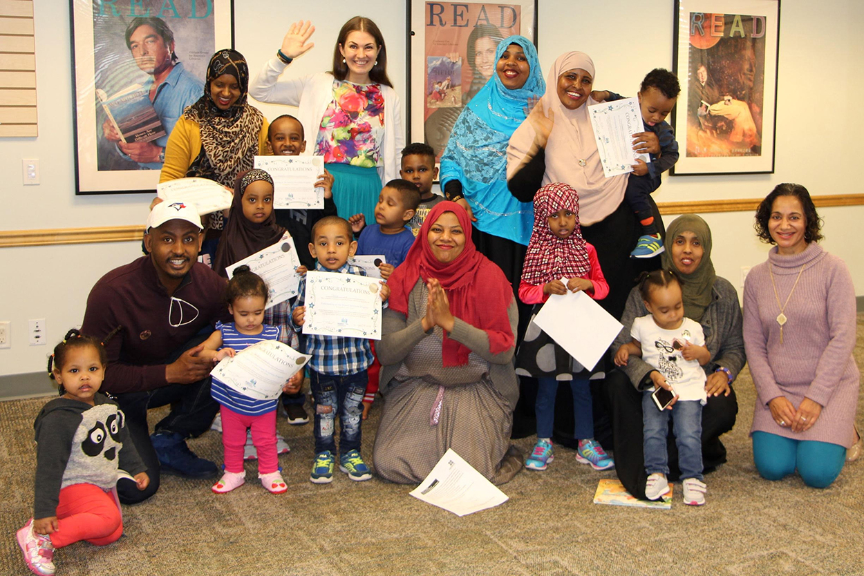 Tania Thomas (waving, back row) credits Options Community Services settlement worker Ikram Araya (centre, front row) and Surrey Libraries manager of multicultural services Ravi Basi (far right, front) for their community consultation and grant applications as well as interpreter Said Mumin (front left) for making the programs possible.